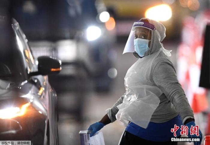 當(dāng)?shù)貢r(shí)間12月18日，英國(guó)政府公布的數(shù)據(jù)顯示，當(dāng)天英國(guó)新增奧密克戎毒株感染病例10059例。鑒于奧密克戎毒株感染病例激增，住院人數(shù)不斷上升，倫敦市長(zhǎng)宣布倫敦進(jìn)入“重大事故”狀態(tài)。圖為倫敦的一個(gè)免下車檢測(cè)中心，一名醫(yī)務(wù)工作者正準(zhǔn)備對(duì)司機(jī)進(jìn)行核酸檢測(cè)。