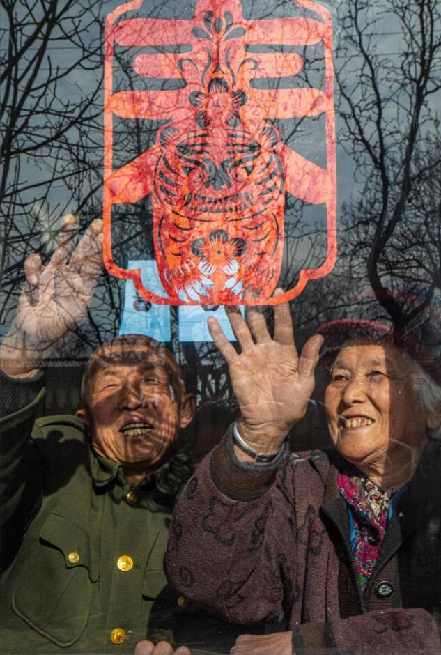 臘月里，霍州市師莊鄉(xiāng)馮南垣村村民師榮光(左)在災(zāi)后重建的新家里貼窗花。(霍州市委宣傳部供圖)