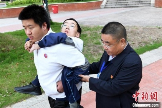 朱金祥背著鐘華強去教室上課的路上，也經(jīng)常碰到值班的校領(lǐng)導(dǎo)和老師前來搭把手。 卓忠偉 攝