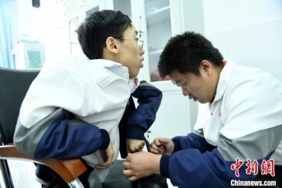 江西省南康中學(xué)北校區(qū)的高三學(xué)生朱金祥(右)正在給鐘華強(左)系好鞋帶。 卓忠偉 攝