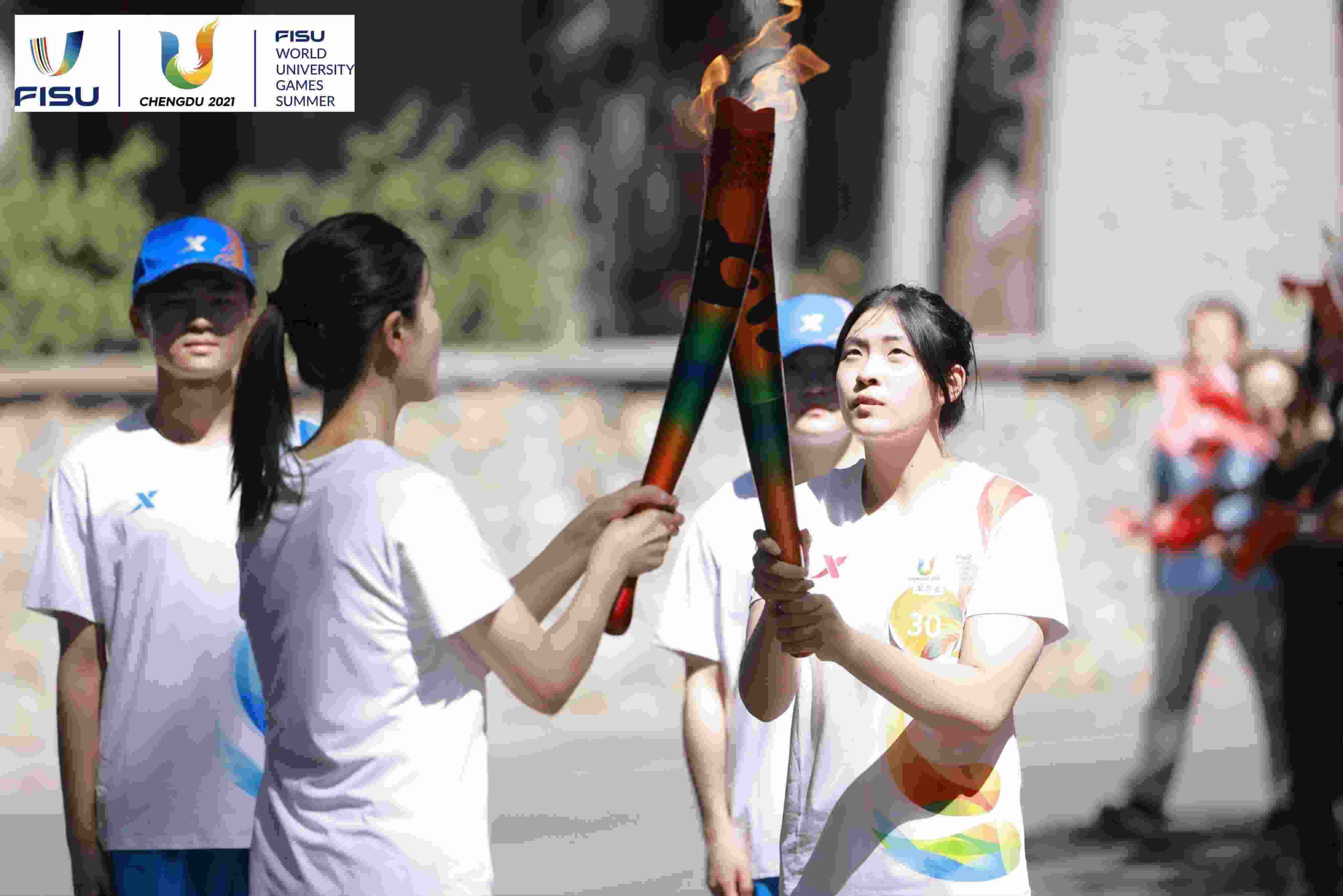 兩名大運(yùn)會(huì)火炬手進(jìn)行火炬?zhèn)鬟f。 圖片來(lái)源：成都大運(yùn)會(huì)執(zhí)委會(huì)供圖