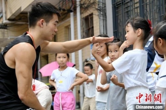 圖為大學(xué)生志愿者在組織孩子們參加體育健身活動(dòng)。廖光福 攝