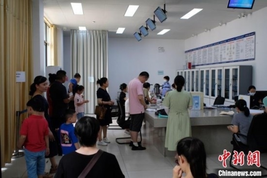 圖為在戶籍辦證廳內(nèi)排隊等待的家長和孩子。劉俊聰 攝