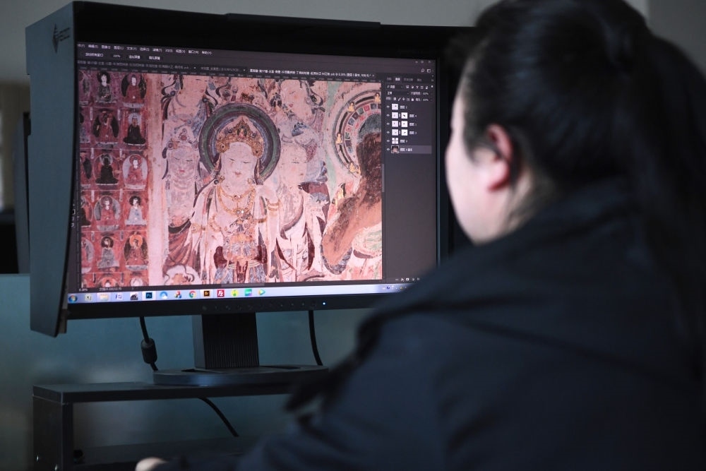 敦煌研究院文物數(shù)字化保護(hù)團(tuán)隊(duì)圖像處理人員年海麗在拼接壁畫圖像（2023年4月25日攝）。數(shù)字化探索為莫高窟的保護(hù)與傳承開辟了全新路徑，數(shù)字技術(shù)讓敦煌文物走出洞窟，跨出國(guó)門，走向“永久保存、永續(xù)利用”。新華社記者 陳斌 攝