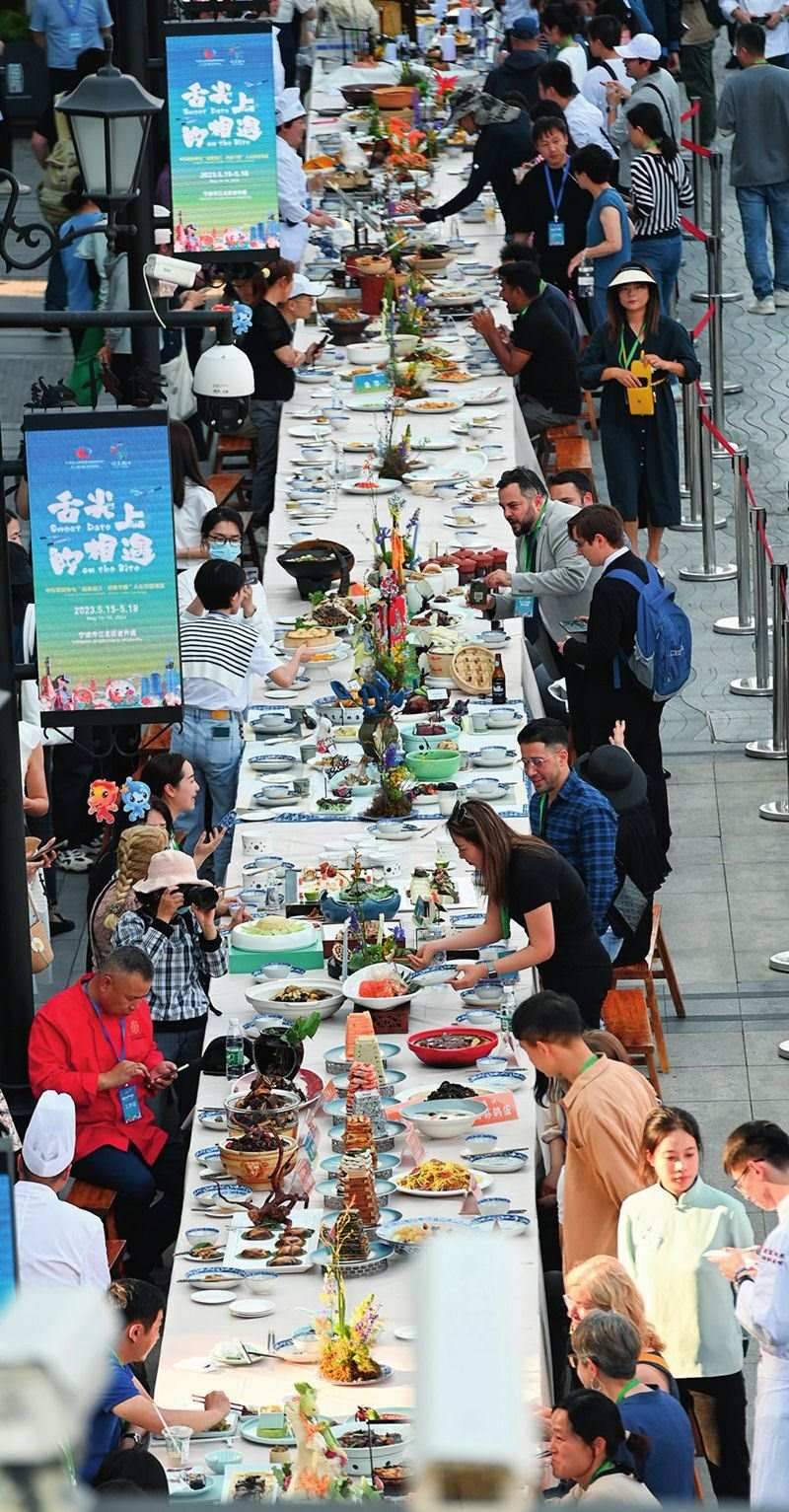 市民和游客在寧波舉辦的第三屆中國(guó)—中東歐國(guó)家博覽會(huì)暨國(guó)際消費(fèi)品博覽會(huì)上品嘗融合中國(guó)和中東歐美食的長(zhǎng)桌宴（2023年5月15日攝）。黃宗治攝/本刊