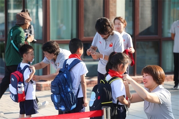 8月30日，雄安史家胡同小學學生體驗學校生活。老師為學生佩戴校徽。
