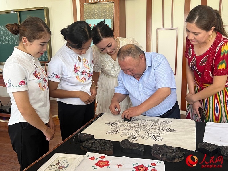 國家級非物質(zhì)文化遺產(chǎn)模戳印花布技藝傳承人吾吉阿西木?吾舒爾展示模戳印花布的制作過程。人民網(wǎng)記者 常雪梅攝