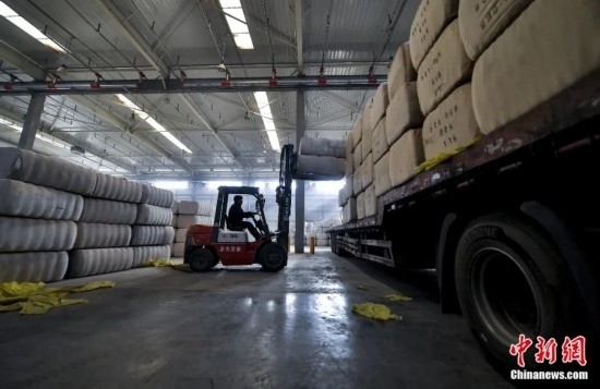 新疆喀什綜合保稅區(qū)，喀什啟路國(guó)際貿(mào)易有限公司的倉(cāng)庫(kù)內(nèi)，工人正在裝載從塔吉克斯坦和烏茲別克斯坦進(jìn)口的棉花。劉新攝