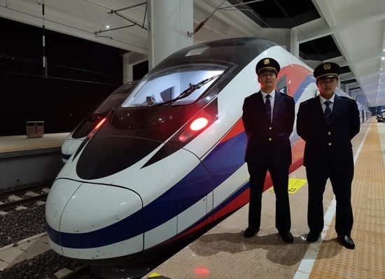 劉銀能（右一）與中國(guó)師父鄔俊鴻在動(dòng)車組前合影。受訪者供圖