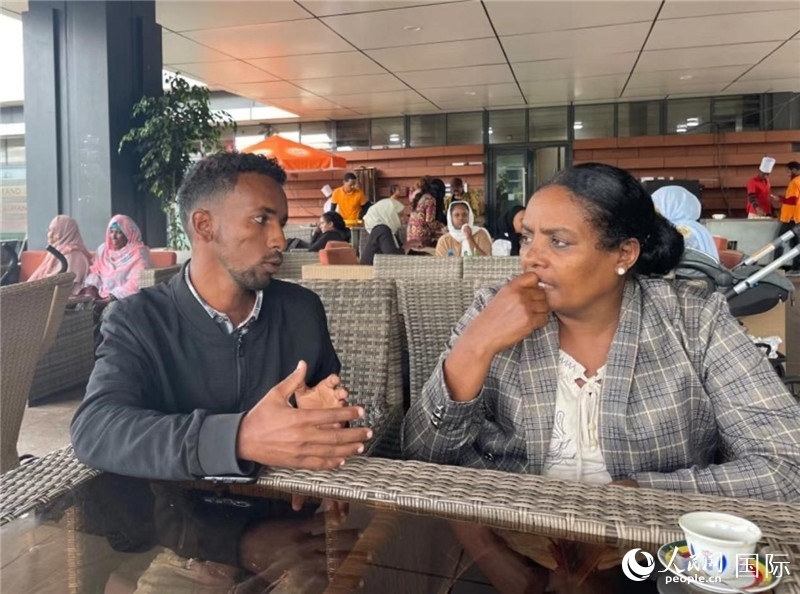 約漢斯（圖左）與德貝拉在友誼廣場(chǎng)咖啡廳交談。人民網(wǎng)記者 趙艷紅攝