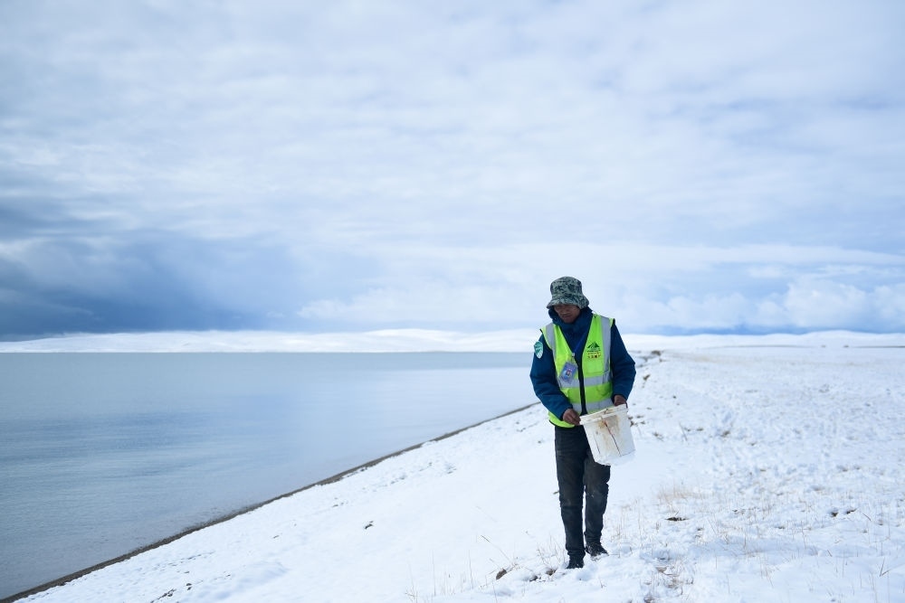 2021年10月20日，在青海省果洛藏族自治州瑪多縣扎陵湖鄉(xiāng)勒那村，三江源國(guó)家公園黃河源園區(qū)生態(tài)管護(hù)員在扎陵湖邊撿拾垃圾。新華社記者 張龍 攝
