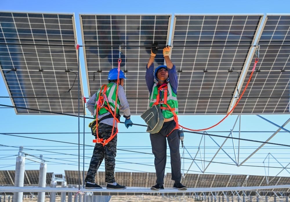 2023年7月22日，工人在位于內(nèi)蒙古杭錦旗庫(kù)布其沙漠億利生態(tài)示范區(qū)的蒙西基地庫(kù)布其200萬(wàn)千瓦光伏治沙項(xiàng)目工地安裝光伏板。新華社記者 劉磊 攝