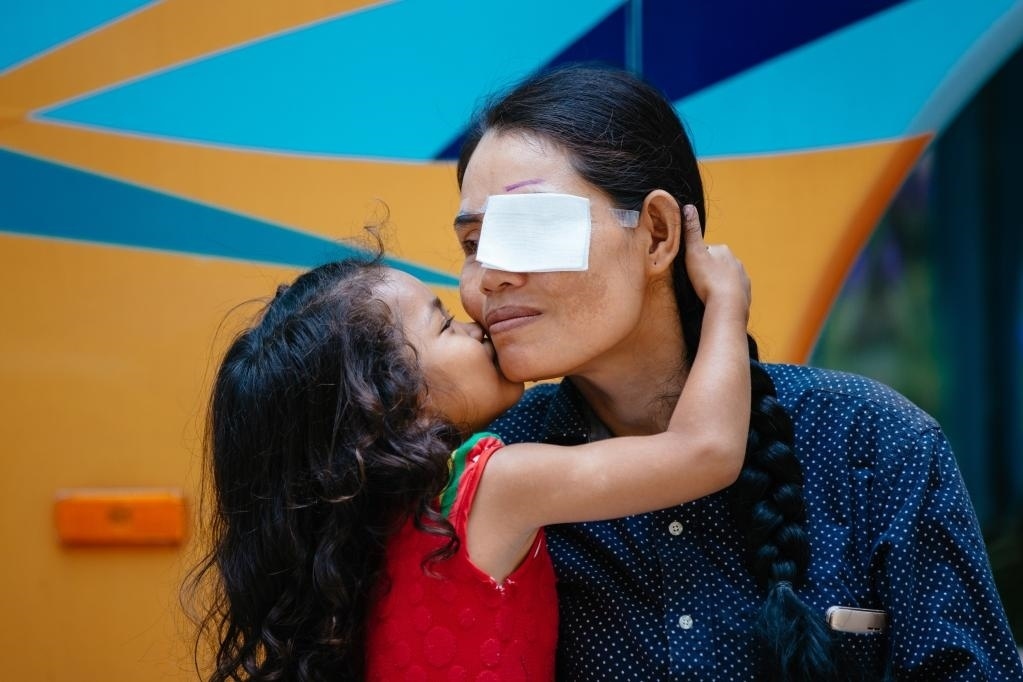 2019年3月15日，在柬埔寨磅湛省醫(yī)院，即將接受白內(nèi)障手術(shù)的患者孫美樂接受女兒的親吻祝福。在接受了中國醫(yī)療隊的白內(nèi)障義診手術(shù)后，她的視力逐步恢復(fù)，生活有了新的光明和希望。