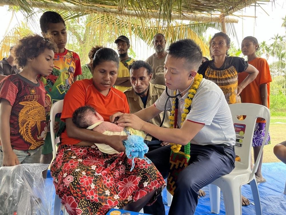 2023年8月5日，在巴布亞新幾內(nèi)亞中央省的一個(gè)村莊里，第12批援巴新中國(guó)醫(yī)療隊(duì)副隊(duì)長(zhǎng)、新生兒科副主任醫(yī)師劉振球?yàn)楫?dāng)?shù)貗雰郝犜\檢查。新華社發(fā)（第12批援巴新中國(guó)醫(yī)療隊(duì)供圖）