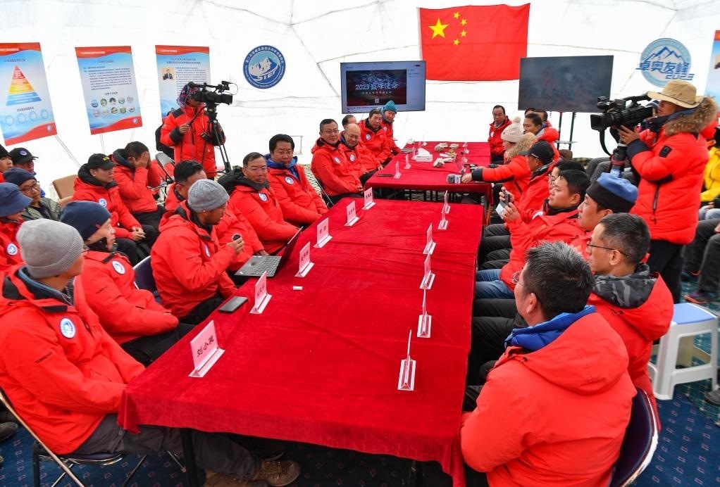 海拔4950米的卓奧友峰科考大本營，科考隊員趙華標(biāo)（手拿麥克風(fēng)看電腦者）在宣讀剛剛接收到的頂峰氣象觀測數(shù)據(jù)，這標(biāo)志著峰頂自動氣象站架設(shè)成功，成功傳回觀測數(shù)據(jù)（10月1日攝）。新華社記者晉美多吉 攝