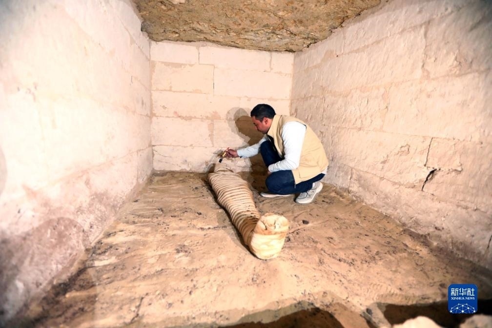 10月15日，在埃及明亞省考古現(xiàn)場，考古人員清理一座石鑿墓中的木乃伊。新華社發(fā)（艾哈邁德·戈馬攝）