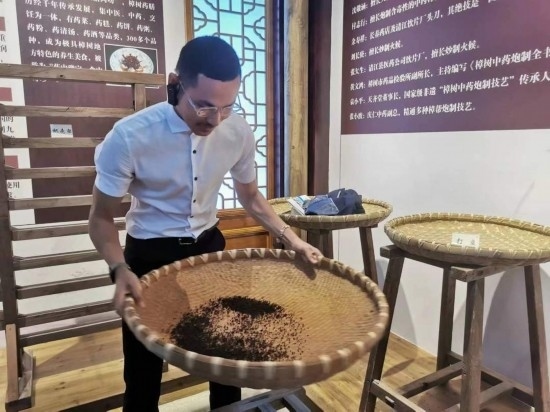 2023“一帶一路”媒體合作論壇聯(lián)合采訪團團員在非遺文化展示館體驗中藥炮制技藝。（本報記者 黃超攝）