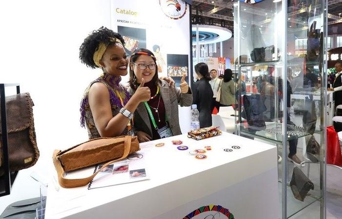 11月6日，一位參觀者（右）在第六屆進(jìn)博會(huì)國(guó)家展南非展臺(tái)試戴傳統(tǒng)首飾。