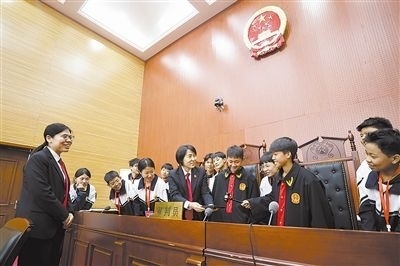 圖③：同學們穿法袍、敲法槌，爭做“小法官”。