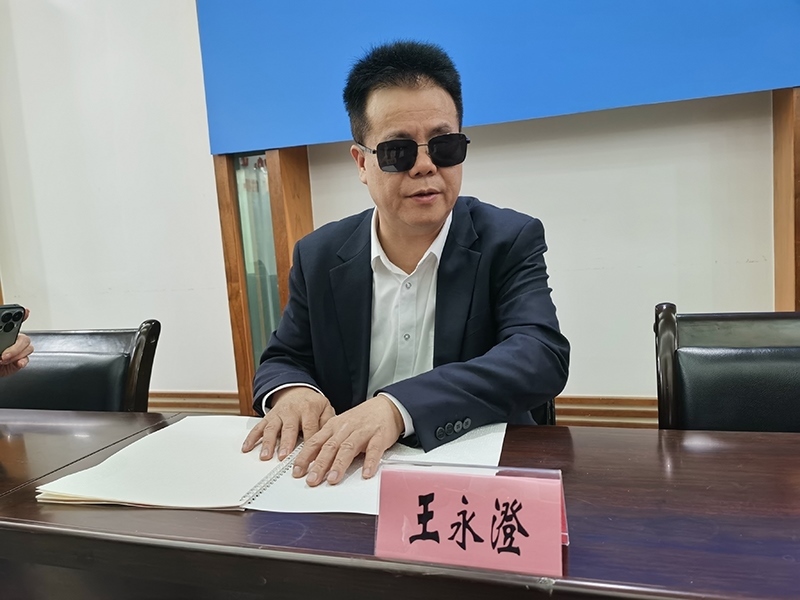 全國(guó)人大代表王永澄正在閱讀盲文版代表建議答復(fù)。本報(bào)記者 張 璁?dāng)z