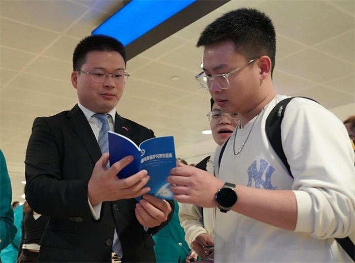 工作人員（左一）在發(fā)放《中國領(lǐng)事保護與協(xié)助指南》。 中國駐迪拜總領(lǐng)事館供圖