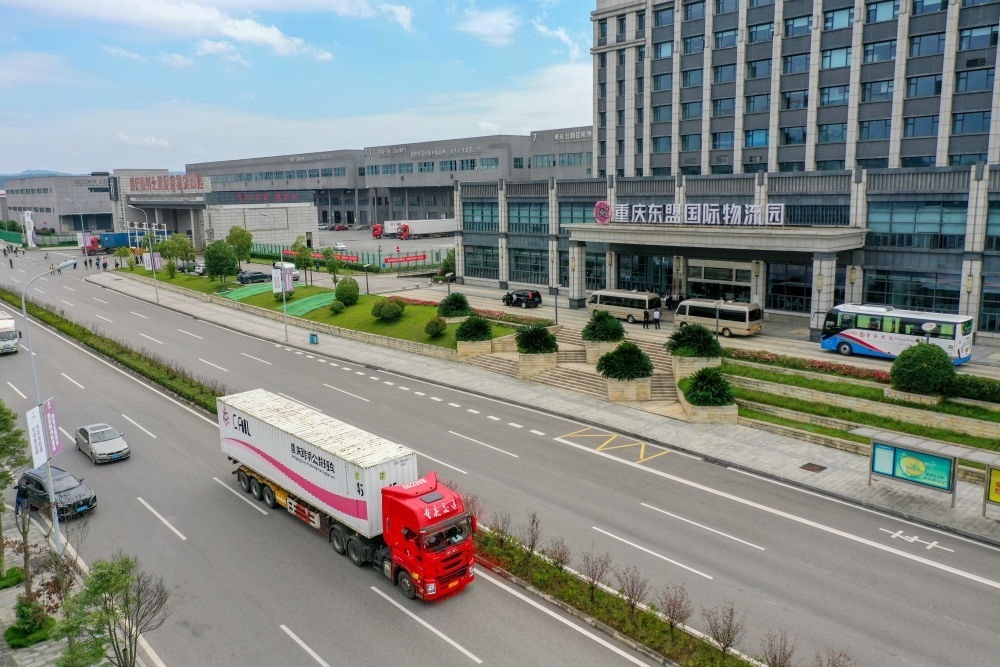 2023年10月11日，滿(mǎn)載筆記本電腦配件、發(fā)電機(jī)組件等產(chǎn)品的西部陸海新通道跨境公路班車(chē)從重慶南彭公路保稅物流中心駛出，將途經(jīng)廣西憑祥，直達(dá)越南（無(wú)人機(jī)照片）。新華社記者 黃偉 攝