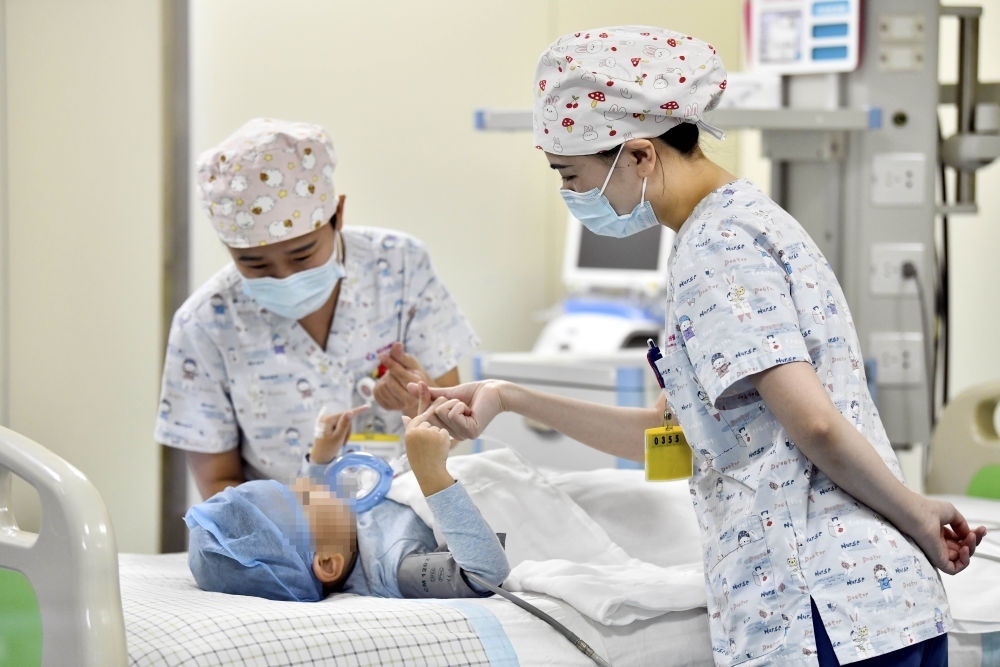 在山東省棗莊市婦幼保健院兒童ICU病房，醫(yī)護人員為完成靶向治療藥物諾西那生鈉的4歲脊髓性肌萎縮癥患兒加油鼓勁（2022年1月1日攝）。諾西那生鈉注射液是我國首個獲批治療脊髓性肌萎縮癥的進口藥物，2019年進入中國市場時，每針價格近70萬元。在2021年國家醫(yī)保目錄藥品談判中，以3.3萬元每針的價格進入新版醫(yī)保藥品目錄。新華社記者 郭緒雷 攝