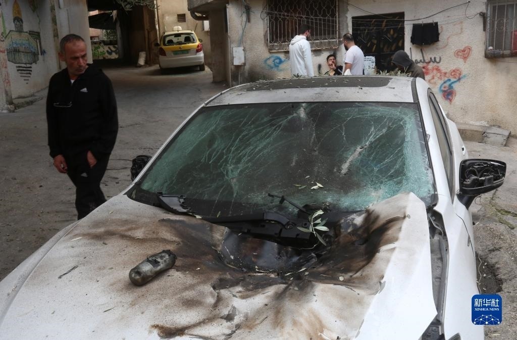 12月17日，在約旦河西岸城市圖勒凱爾姆附近的一處難民營，人們查看在沖突中損毀的車輛。新華社發(fā)（尼達爾·艾仕塔耶?dāng)z）