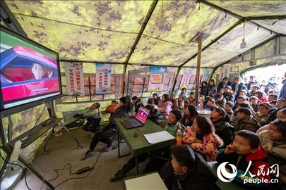 12月22日，在積石山縣大河家鎮(zhèn)大河村安置點，陸軍76集團(tuán)軍某旅搭建的“臨時學(xué)?！眱?nèi)，小朋友正在看動畫片。人民網(wǎng)記者 翁奇羽攝