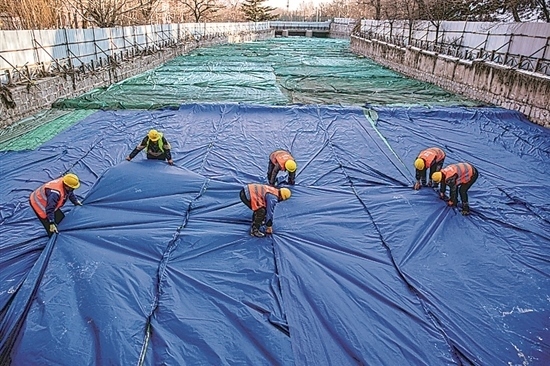 1月3日，房山區(qū)東風(fēng)街道，工人正在修復(fù)的河道內(nèi)給混凝土鋪設(shè)保溫布。