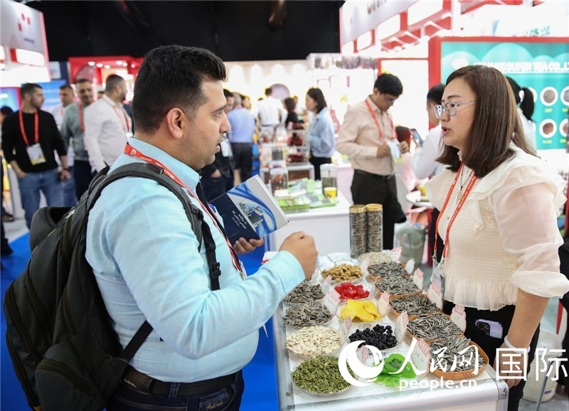 圖為一家中國干果參展企業(yè)代表與采購商洽談。人民網(wǎng) 塔里克·易卜拉欣攝