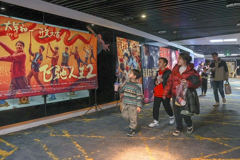 △ 2024年2月16日，在江西贛州一家電影院，觀眾從春節(jié)檔電影的宣傳展板前走過。