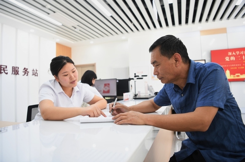 2023年5月23日，河北雄安新區(qū)容東片區(qū)南文營社區(qū)居民（右）在社區(qū)便民服務(wù)站辦理業(yè)務(wù)。