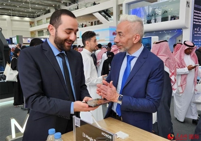 兩名觀眾在榮耀手機展臺前交流。人民網(wǎng)記者 管克江攝