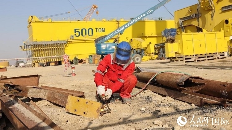 工人正在龍門吊吊裝現(xiàn)場切割金屬件。人民網(wǎng)記者管克江攝