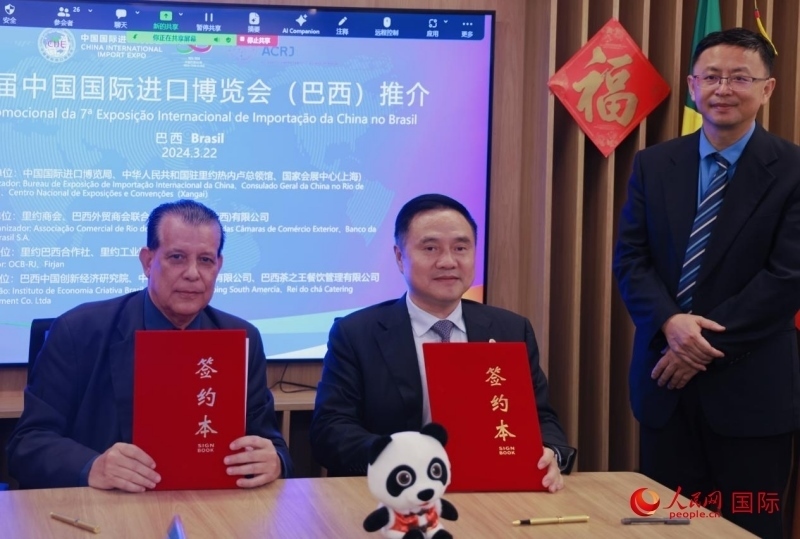 巴西外貿(mào)商會聯(lián)合會會長阿代爾·羅伯托（左）與中國國際進口博覽局副局長吳政平（中）現(xiàn)場簽訂協(xié)議。人民網(wǎng)記者 宋亦然攝