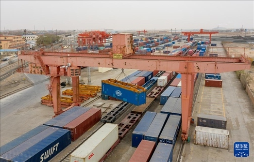 4月21日，二連浩特鐵路口岸龍門吊吊裝中歐班列集裝箱（無人機照片）。 新華社發(fā)（張海峰攝）