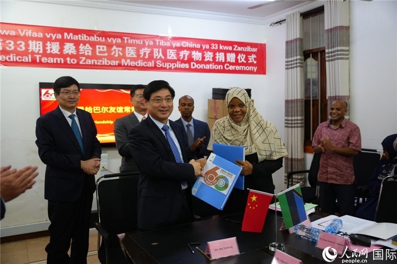 江蘇省蘇北人民醫(yī)院黨委書記束余聲與桑衛(wèi)生部首席秘書哈比巴交換捐贈書。中國援桑醫(yī)療隊供圖