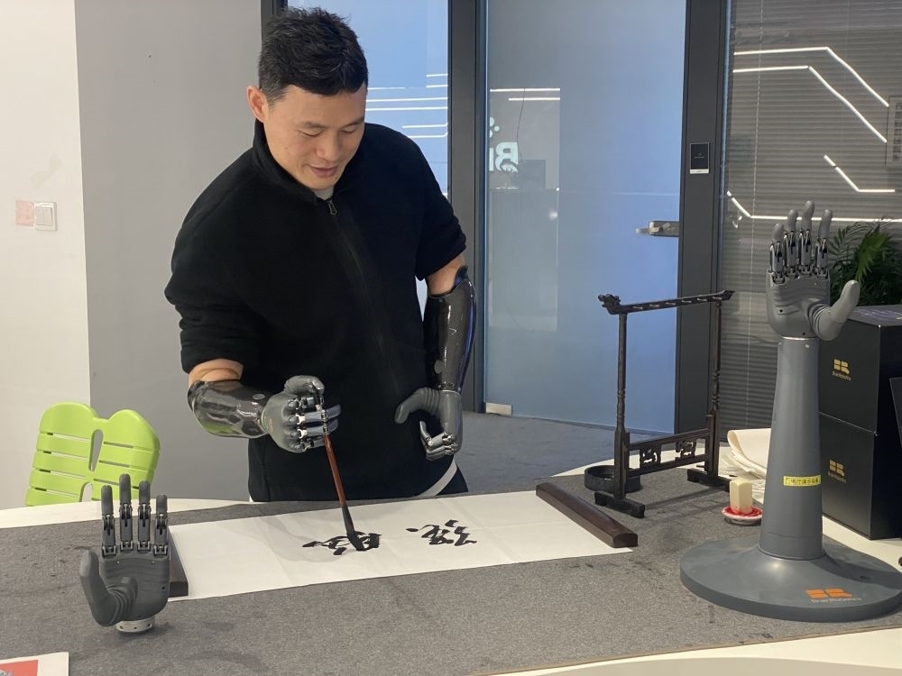 2024年3月29日，在浙江強腦科技有限公司展廳內，失去雙手的產品體驗官倪敏成依靠智能仿生手寫毛筆字。新華社記者 魏一駿 攝