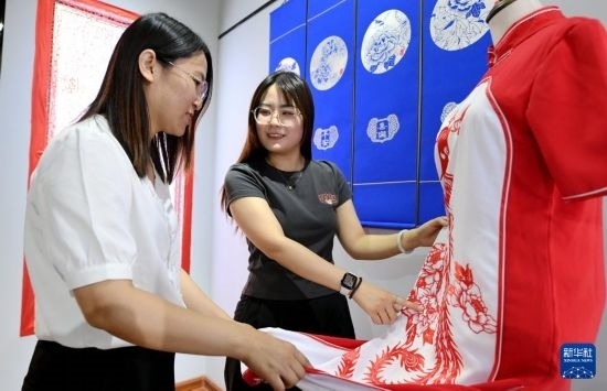 5月31日，在衡水市阜城縣一家剪紙工作室，游客在觀賞帶有剪紙?jiān)氐钠炫邸? width=