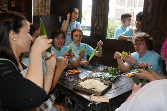 6月9日，美國青年代表在重慶永川松溉古鎮(zhèn)體驗包粽子。新華社記者 周思宇 攝