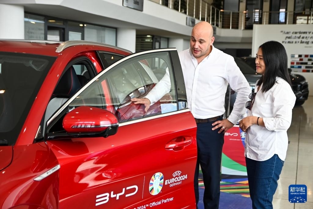 2024年5月29日，在馬耳他比爾基卡拉，馬耳他哈桑-扎米特汽車公司首席執(zhí)行官德古阿拉（左）介紹一輛比亞迪純電動(dòng)汽車。新華社發(fā)（喬納森·博格 攝）