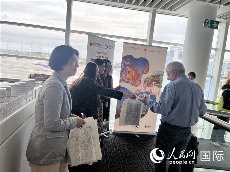 圖為工作人員向乘客發(fā)放復(fù)航首班禮物。 牛瑞飛攝