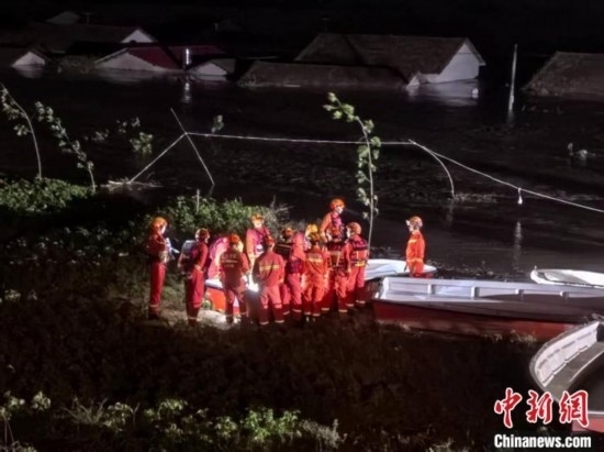  7月6日凌晨3時，在湖南岳陽華容縣團洲垸洞庭湖一線堤防，救援人員剛剛完成一次救援任務(wù)，遠處是被淹的民房。中新社記者 白祖偕 攝