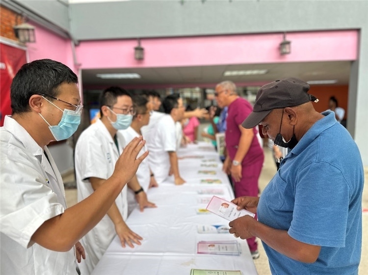 援圭醫(yī)療隊(duì)隊(duì)員們?cè)趩?dòng)儀式上為當(dāng)?shù)孛癖姺职l(fā)宣傳手冊(cè)。中國(guó)援助圭亞那醫(yī)療隊(duì)供圖