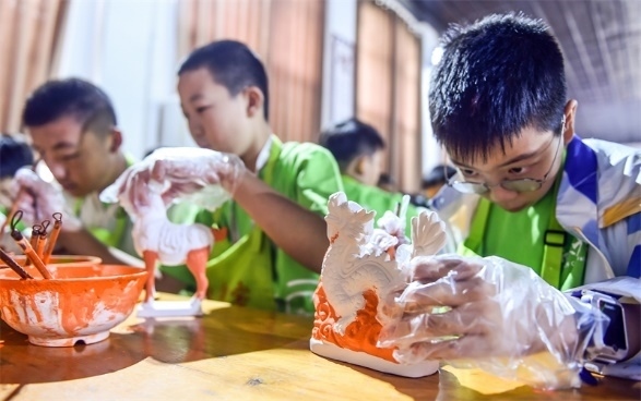 小朋友們在洛陽市孟津區(qū)朝陽鎮(zhèn)南石山村體驗(yàn)唐三彩素胎施釉技藝。圖片來源：視覺中國