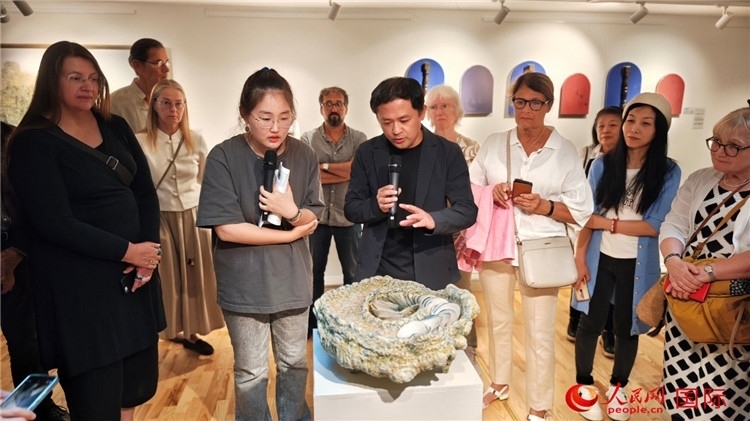 參展人、景德鎮(zhèn)陶瓷大學(xué)設(shè)計(jì)藝術(shù)學(xué)院副院長(zhǎng)余劍峰（中）向來(lái)賓介紹參展作品。人民網(wǎng)記者 殷淼攝