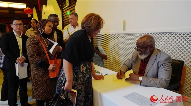 譚哲理在活動(dòng)現(xiàn)場(chǎng)簽名贈(zèng)書(shū)。人民網(wǎng) 劉暢攝