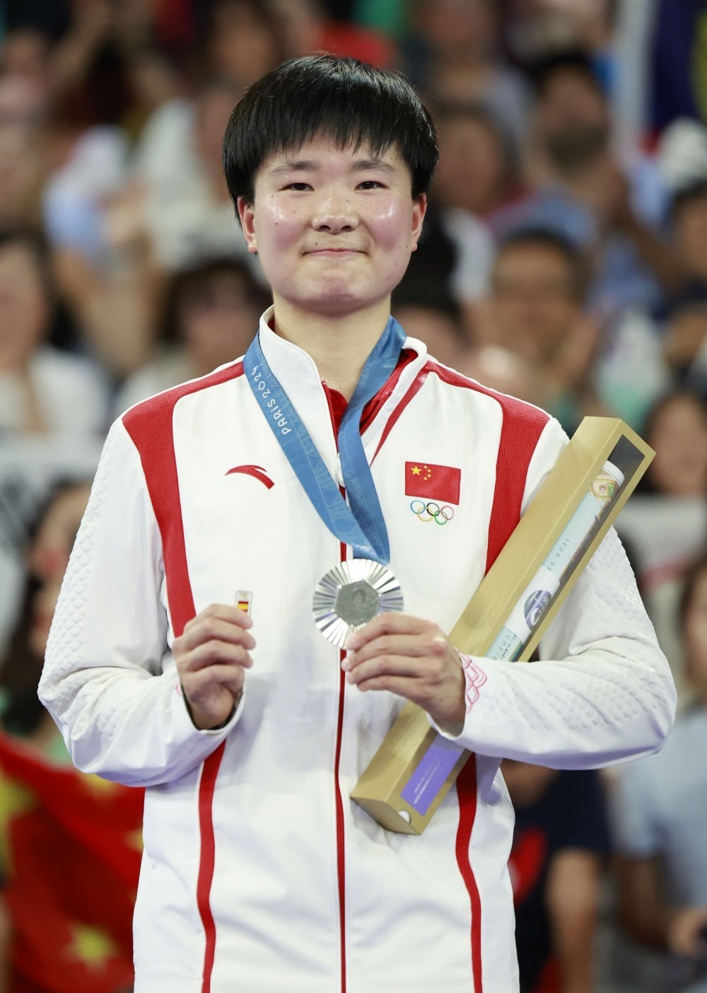 巴黎奧運會羽毛球女子單打亞軍、中國選手何冰嬌在頒獎儀式上一手握著銀牌，一手握著西班牙奧委會徽章（2024年8月5日攝）。新華社記者 任正來 攝