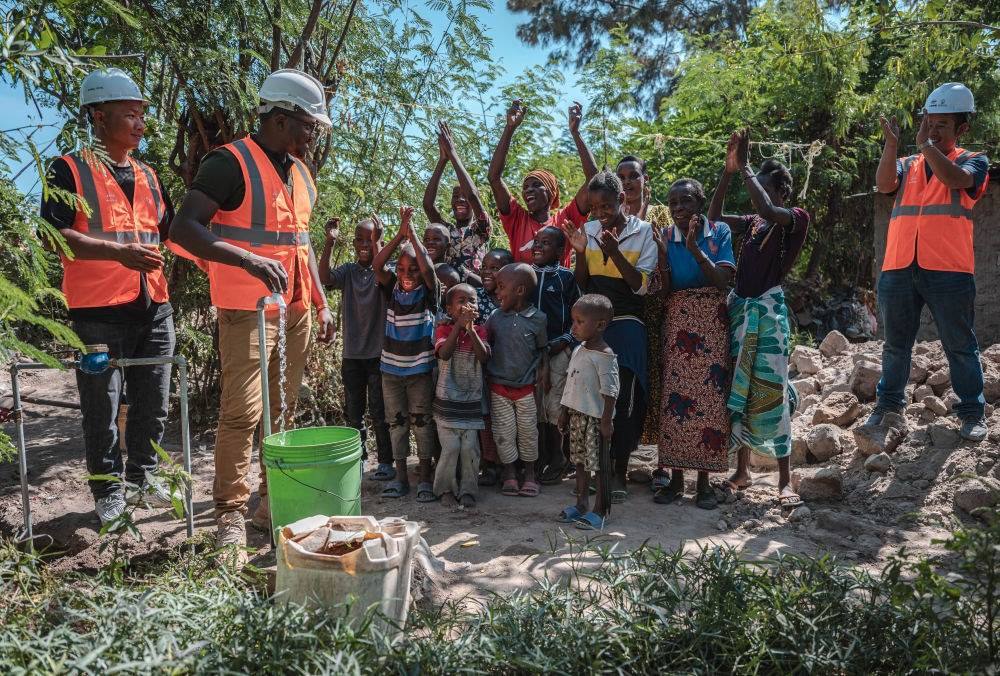 2023年6月13日，在坦桑尼亞姆萬(wàn)扎省米松圭，工作人員接通水管后贏得當(dāng)?shù)鼐用窆恼茪g呼。新華社記者 王冠森 攝